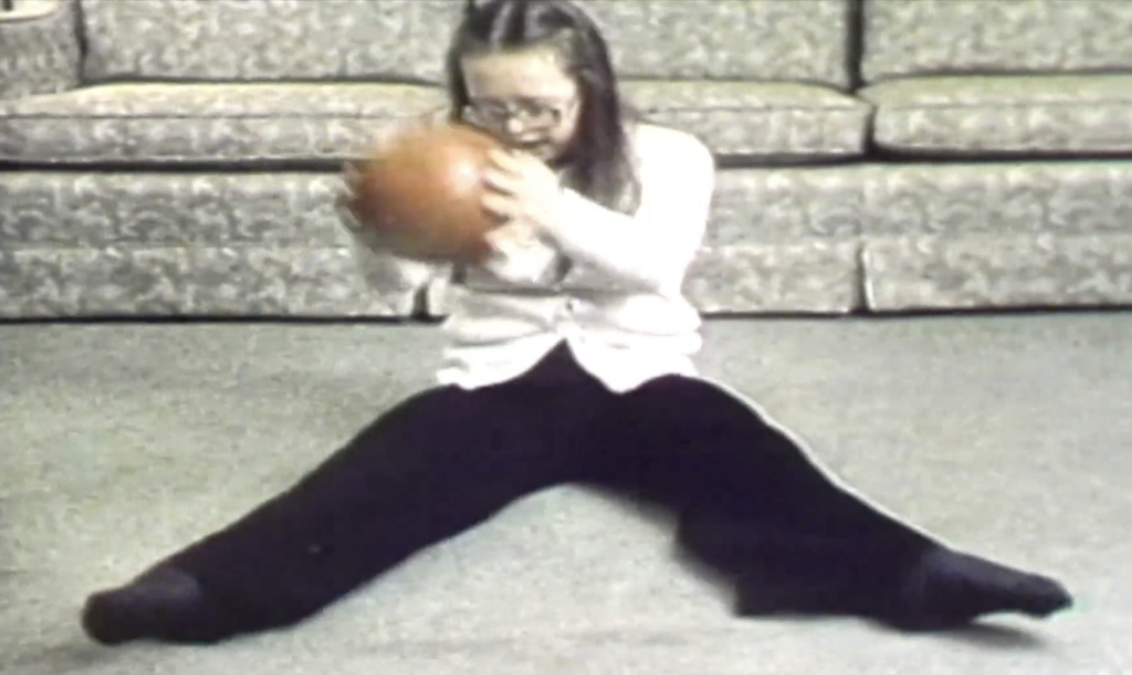 Teresa Heartchild at 13, doing her Swedish Ball routine in the documentary Exploding the Myth. She is wearing a white sweater and black pants. Images and text used with permission from Community Living Ontario